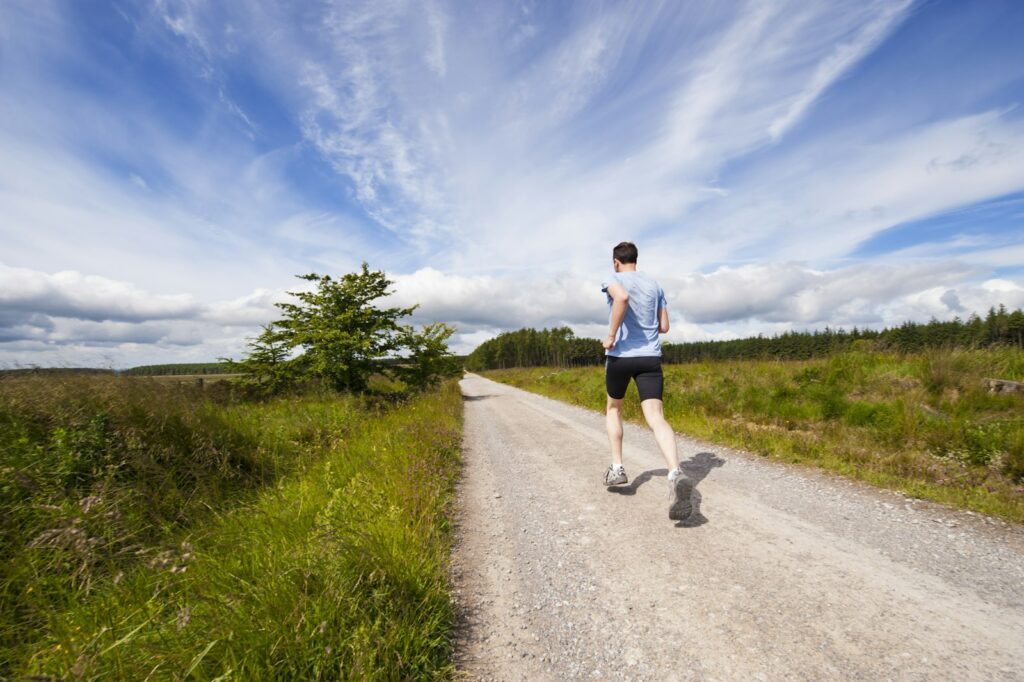 Person running on a path near grasslands — exercise extends healthspan
